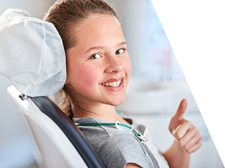 Young girl giving thumbs up during dental checkup and teeth cleaning with children's dentist