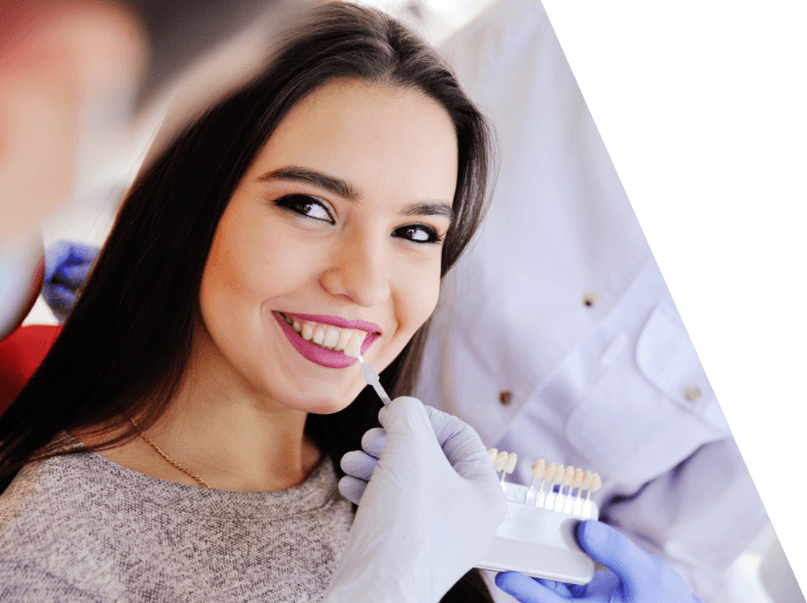Cosmetic dentist comparing woman's smile compared with veneers color option