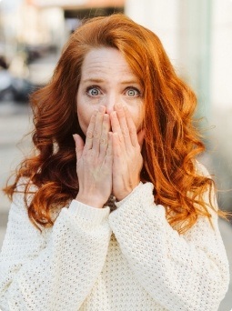 Woman covering her mouth before gum disease treatment