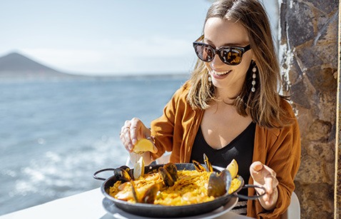 Smiling woman enjoying meal at restaurant on the water