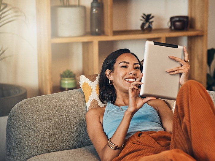 a person relaxing on a couch with their tablet 