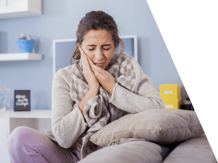 Woman holding cheek in pain before wisdom tooth extractions