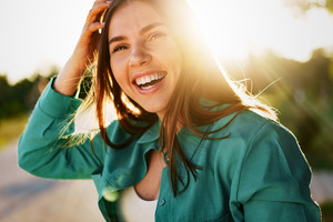 Young woman in green jacket outside and smiling