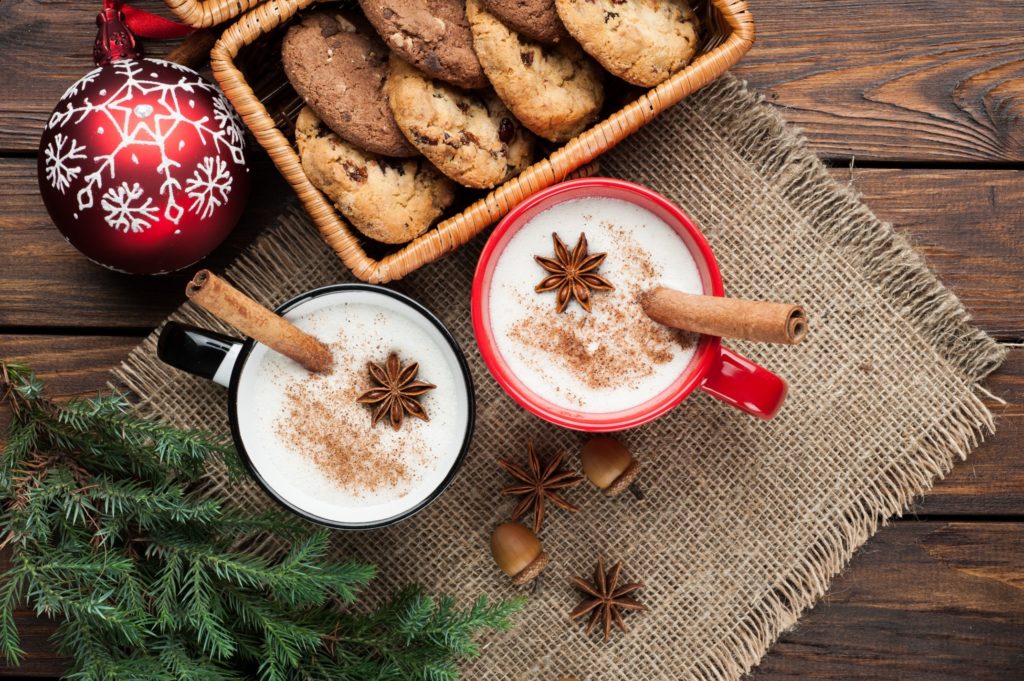 Table with two glasses of eggnog, holiday ornament, and cookies